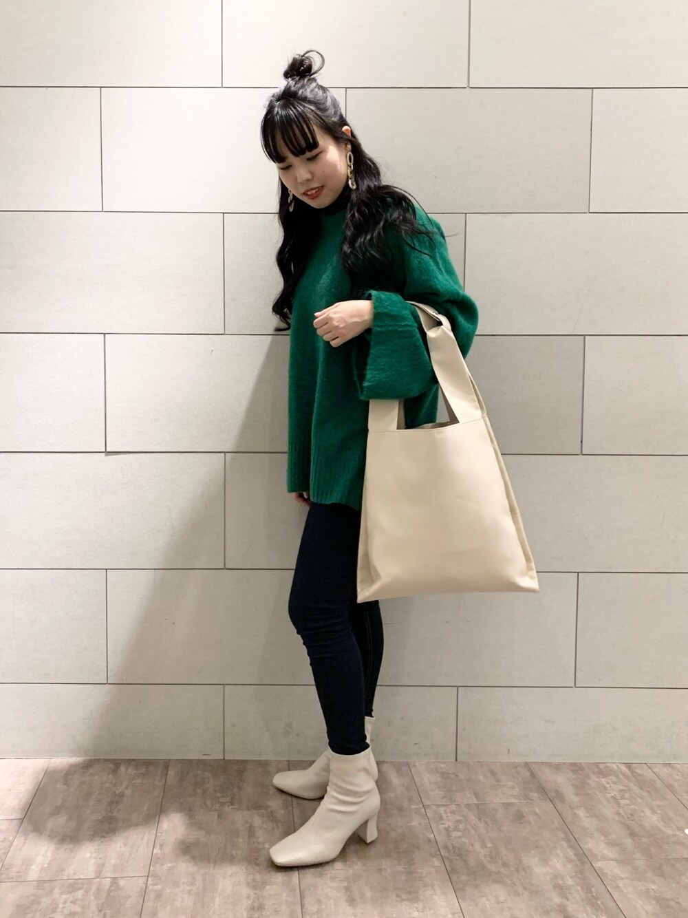 グリーン系のニット/セーター、ブラック系のデニムパンツ、ベージュ系のブーツを着用したレディースの秋コーディネートの1枚目の写真