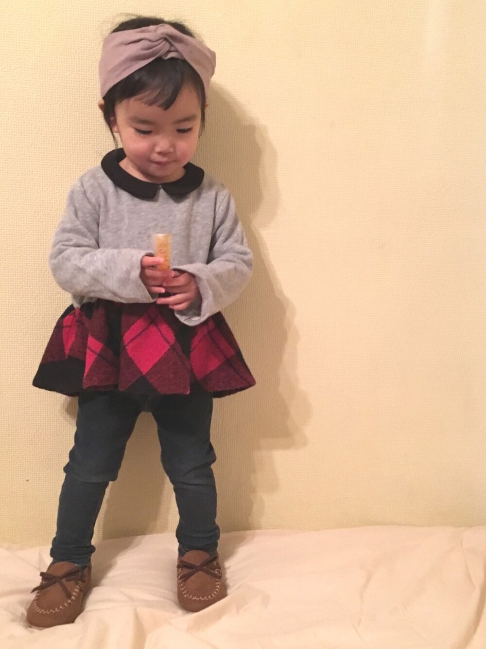 グレー系のチュニック、ブルー系のデニムパンツ、ベージュ系のモカシン/デッキシューズを着用したキッズの冬コーディネートの1枚目の写真