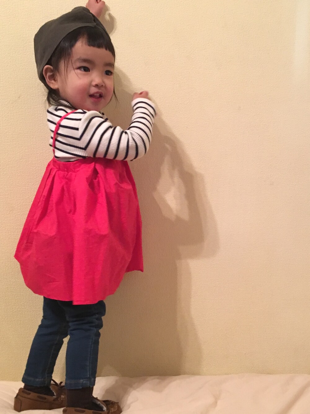 レッド系のワンピース、ブラック系のTシャツ/カットソー、ブルー系のデニムパンツを着用したキッズの冬コーディネートの1枚目の写真