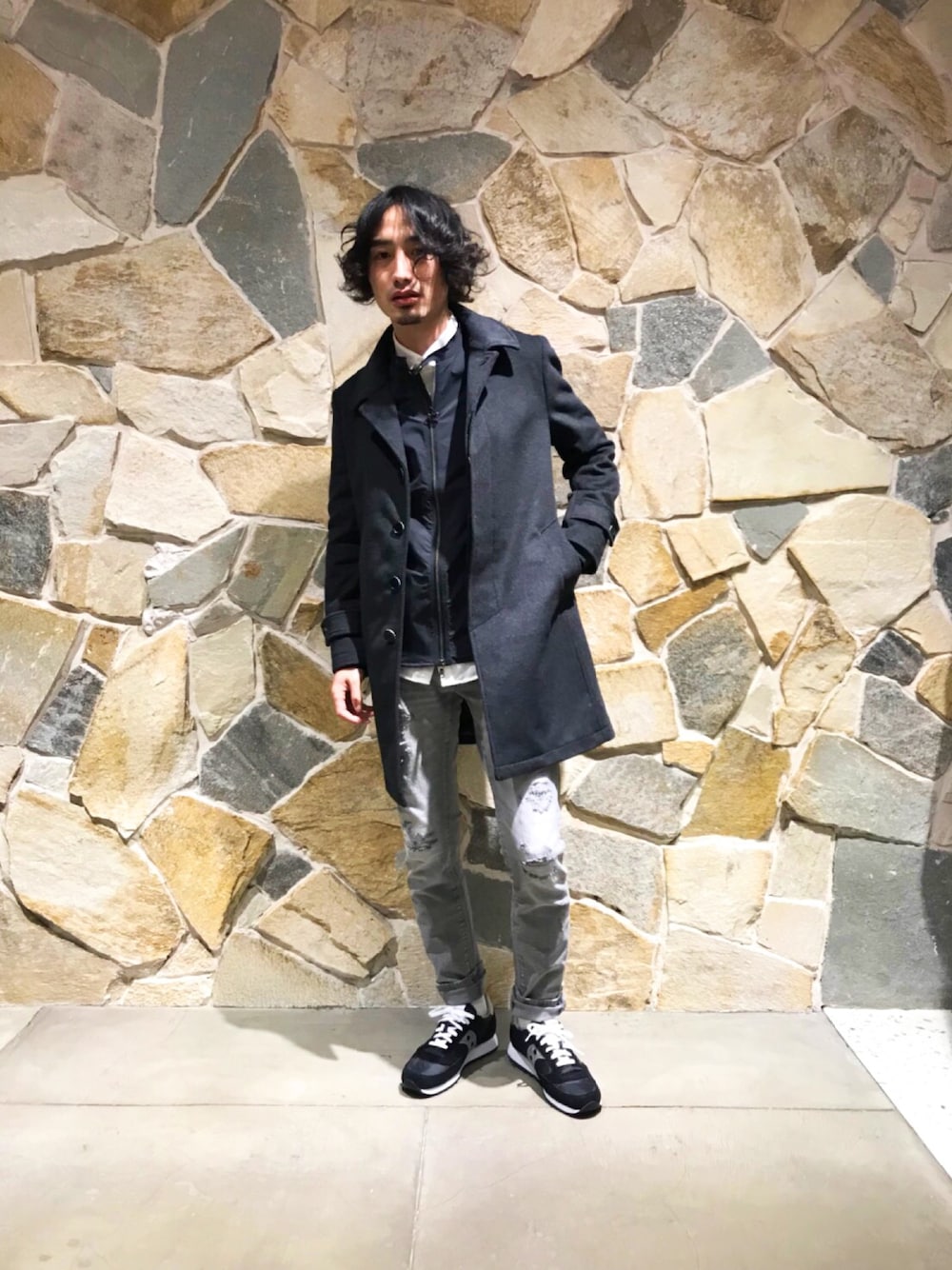 グレー系のステンカラーコート、ブラック系のブルゾン、グレー系のデニムパンツを着用したメンズの冬コーディネートの1枚目の写真