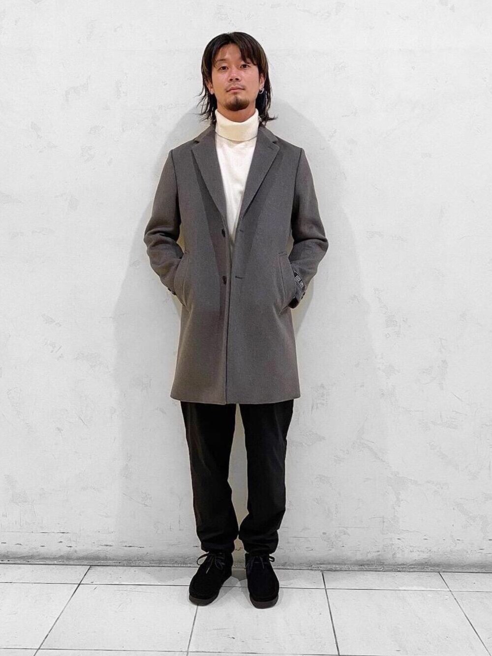 グリーン系のチェスターコート、ホワイト系のニット/セーター、ブラック系のモカシン/デッキシューズを着用したメンズの秋コーディネートの1枚目の写真