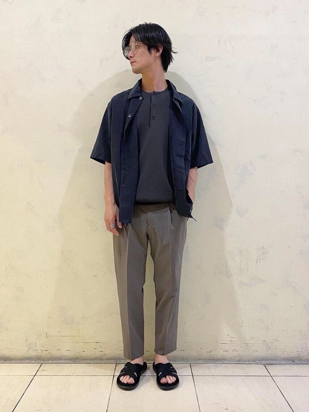 グリーン系のスラックス、ブラック系のシャツ/ブラウス、グレー系のニット/セーターを着用したメンズの春コーディネートの1枚目の写真