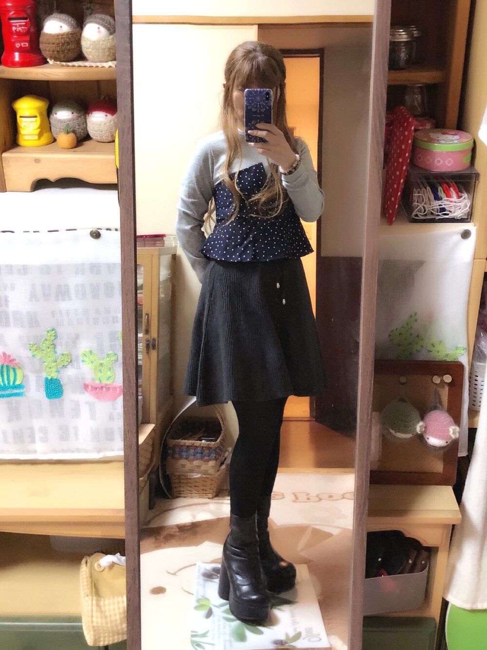グレー系のスカート、ブラック系のブーツ、ブルー系のTシャツ/カットソーを着用したレディースの秋コーディネートの1枚目の写真