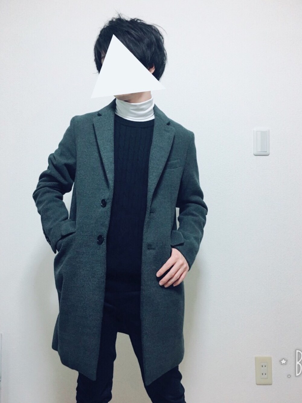 グレー系のチェスターコート、ブラック系のニット/セーター、ブラック系のチノパンツを着用したメンズの冬コーディネートの1枚目の写真