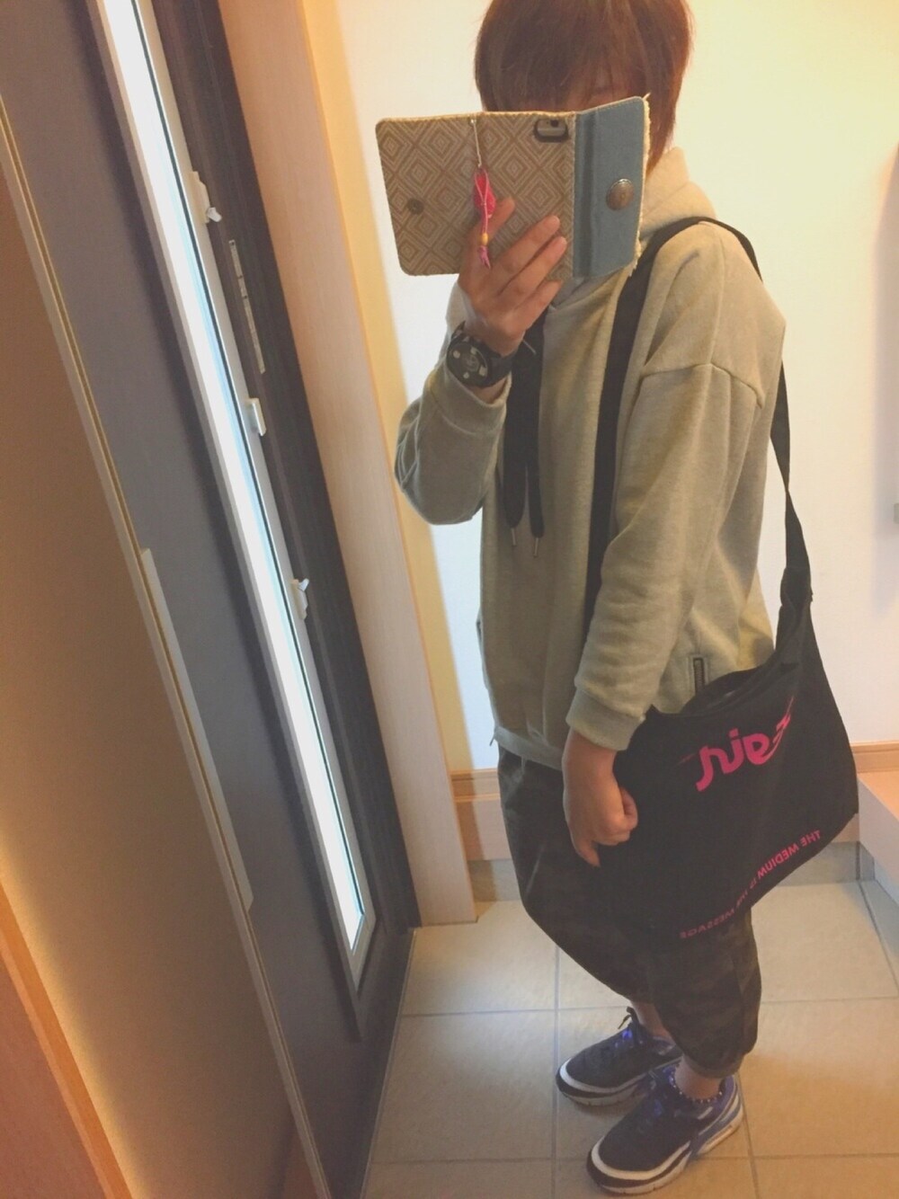 グレー系のパーカー、ベージュ系のパンツ、ブラック系のスニーカーを着用したレディースの春コーディネートの1枚目の写真