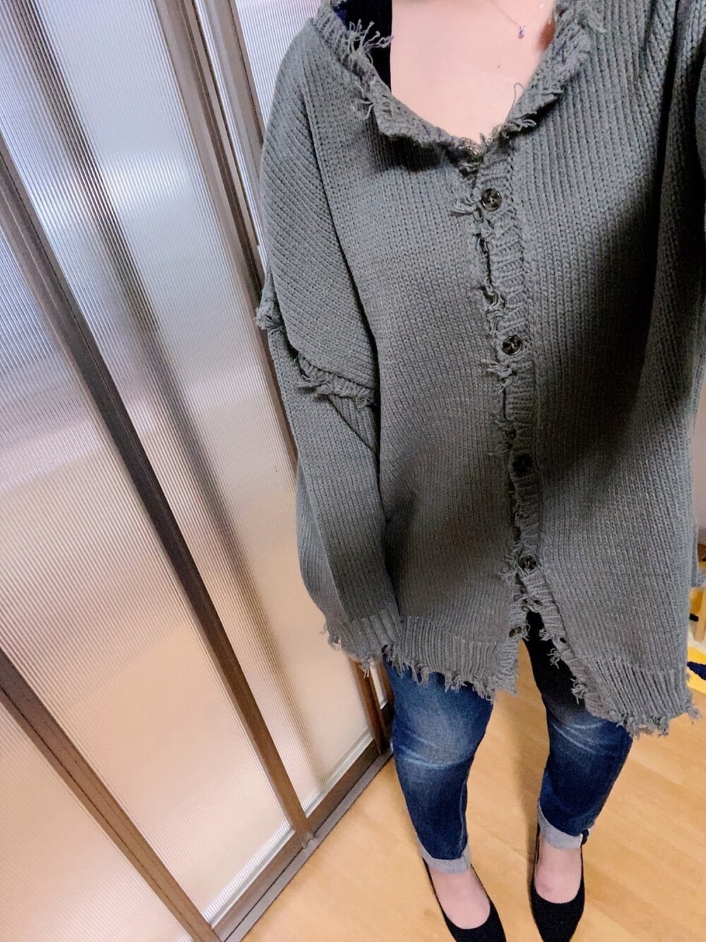 グレー系のニット/セーター、ブルー系のデニムパンツ、ブラック系のブラジャーを着用したレディースの秋コーディネートの1枚目の写真