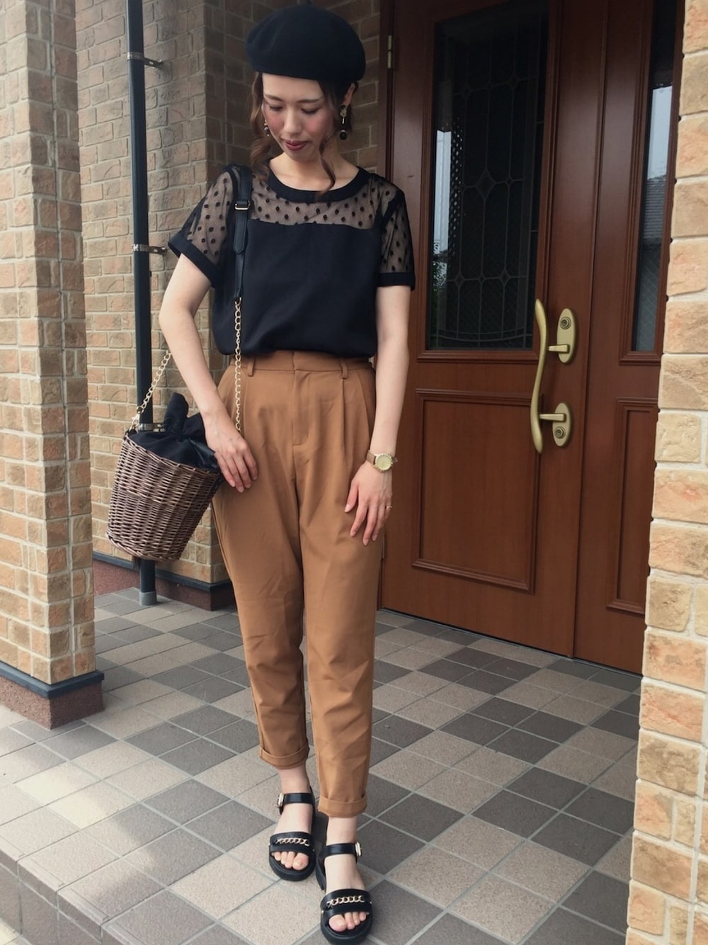 ブラック系のサンダル、ブラウン系のパンツ、ブラック系のかごバッグを着用したレディースの夏コーディネートの1枚目の写真
