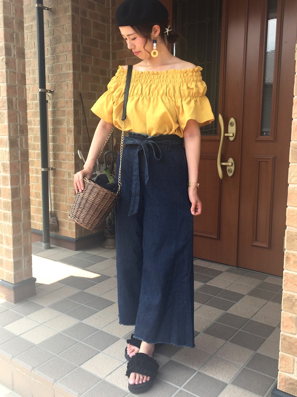 ブルー系のデニムパンツ、ブラック系のかごバッグ、イエロー系のトップスを着用したレディースの夏コーディネートの1枚目の写真