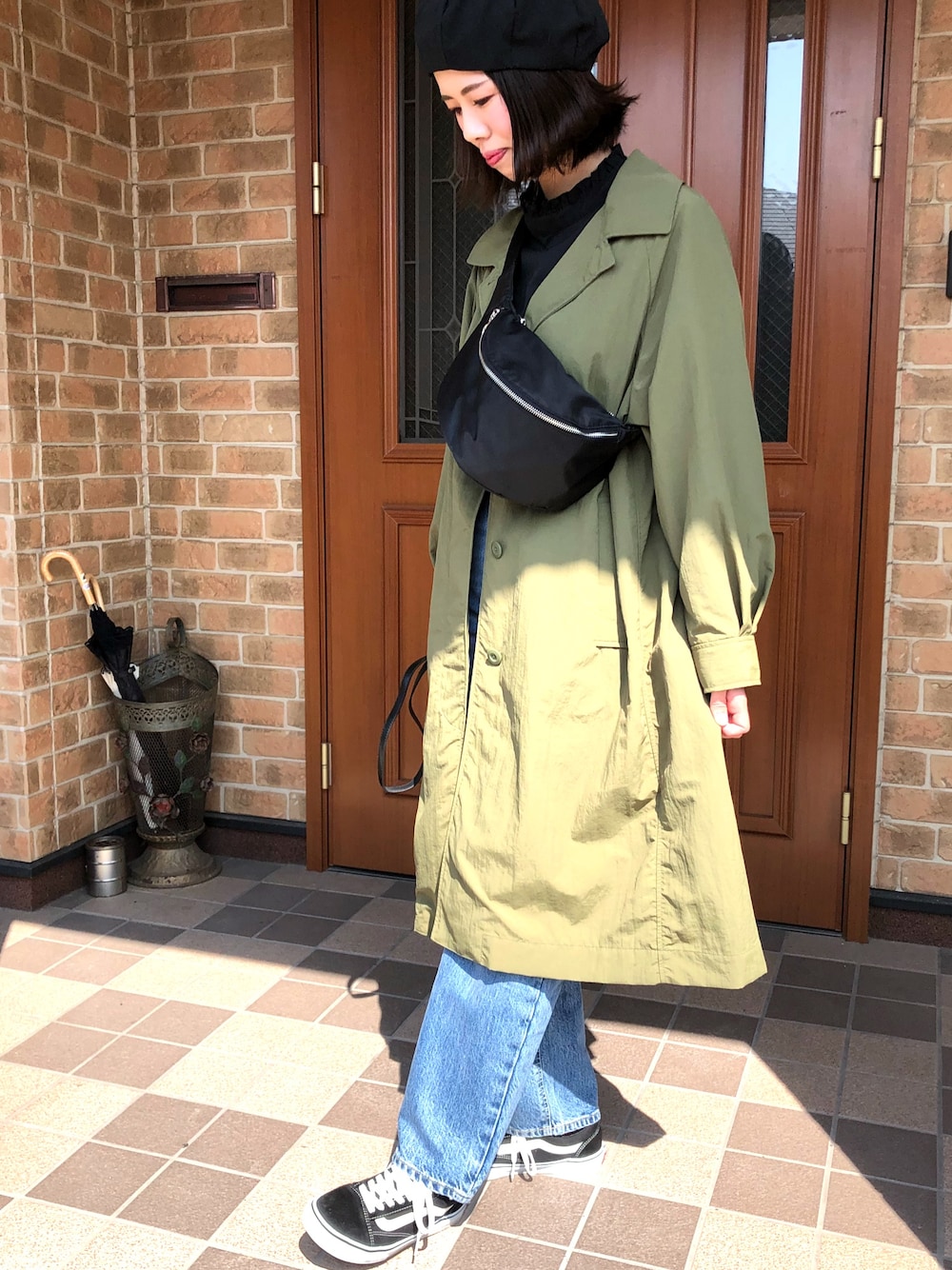 ブラック系のスニーカー、ブルー系のデニムパンツ、グリーン系のジャケット/アウターを着用したレディースの春コーディネートの1枚目の写真