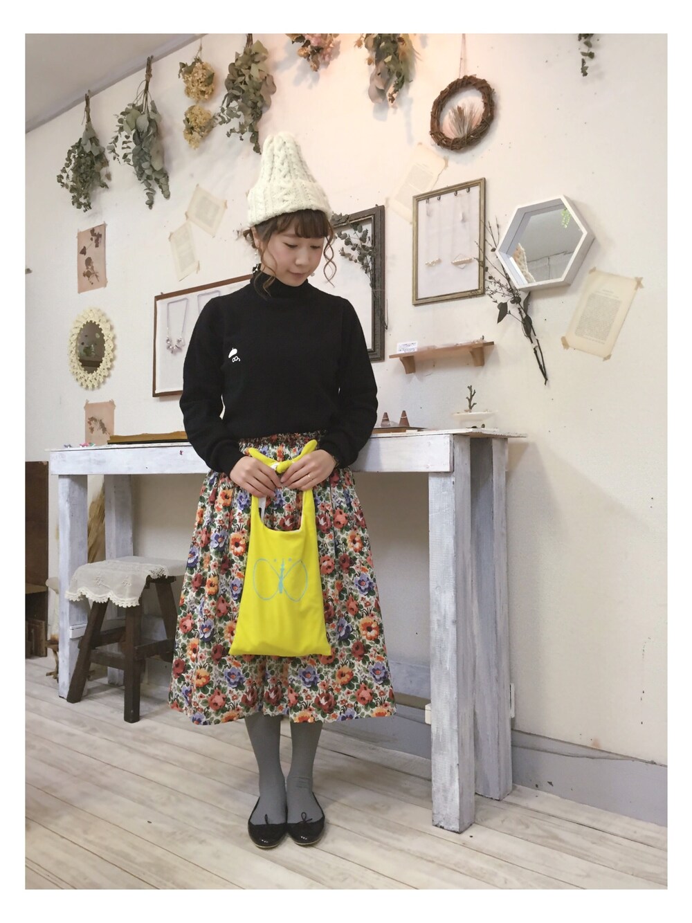 ブラック系のニット/セーター、その他のスカート、イエロー系のハンドバッグを着用したレディースの冬コーディネートの1枚目の写真