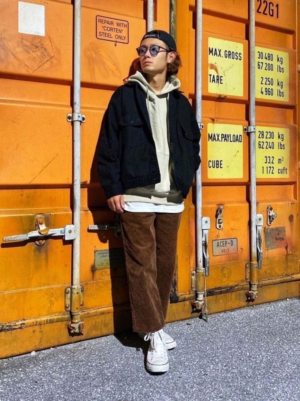 ブラック系のデニムジャケット、ベージュ系のパーカー、ホワイト系のタンクトップを着用したメンズの秋コーディネートの1枚目の写真