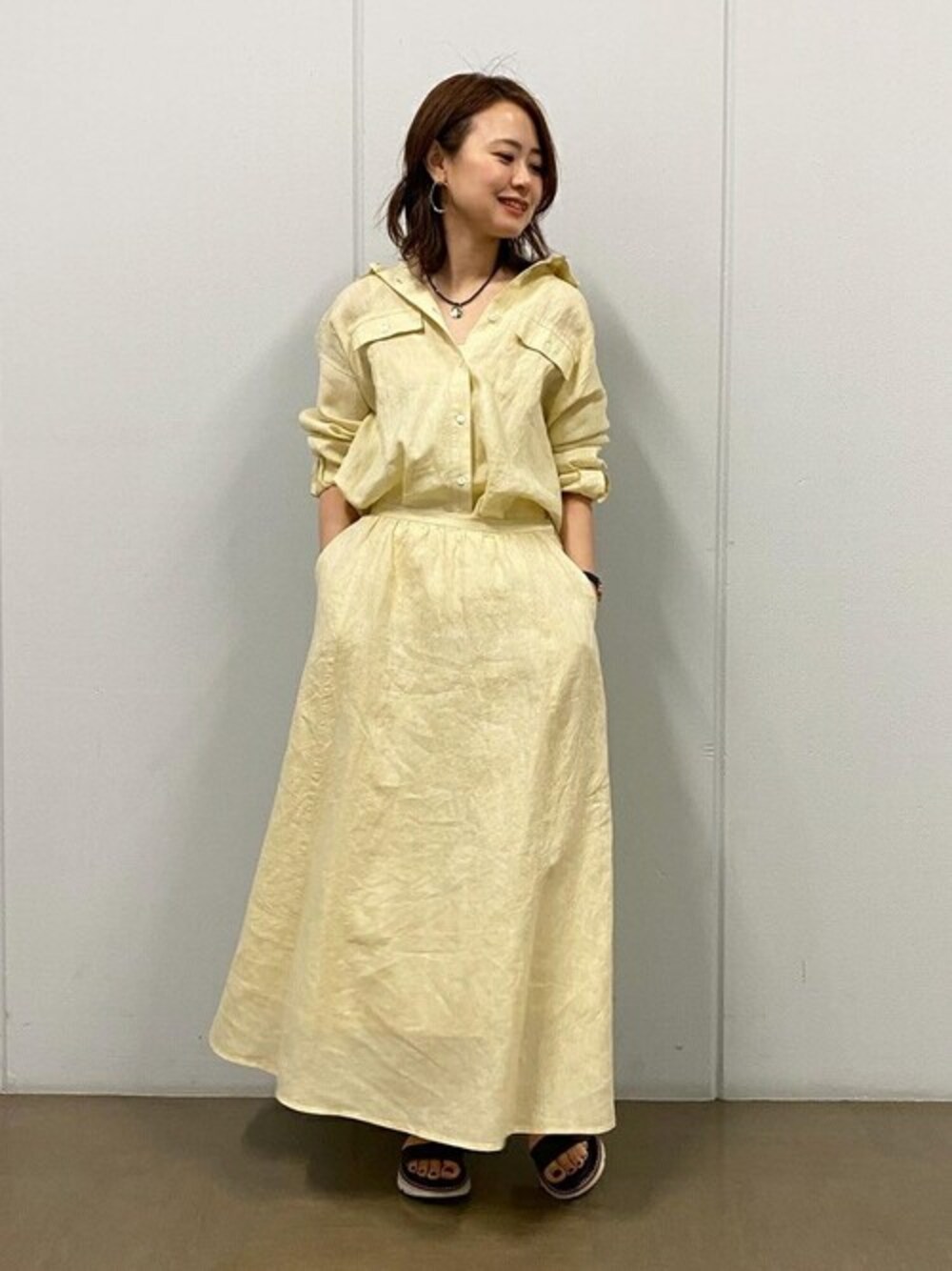 イエロー系のシャツ/ブラウス、イエロー系のスカート、ブラウン系のサンダルを着用したレディースの春コーディネートの1枚目の写真