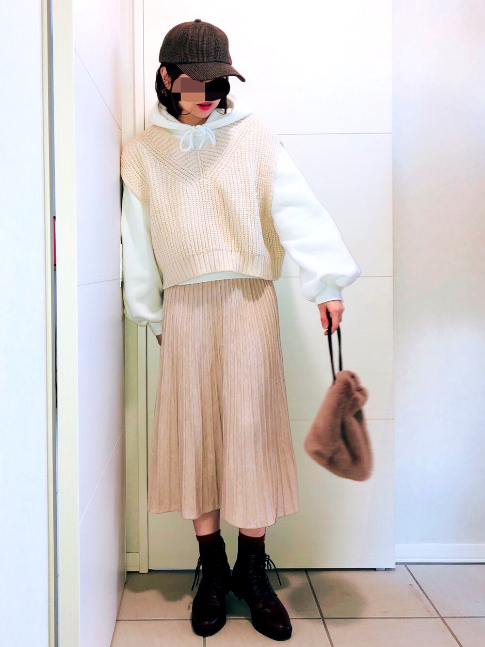 ホワイト系のパーカー、ベージュ系のベスト、ベージュ系のスカートを着用したレディースの冬コーディネートの1枚目の写真