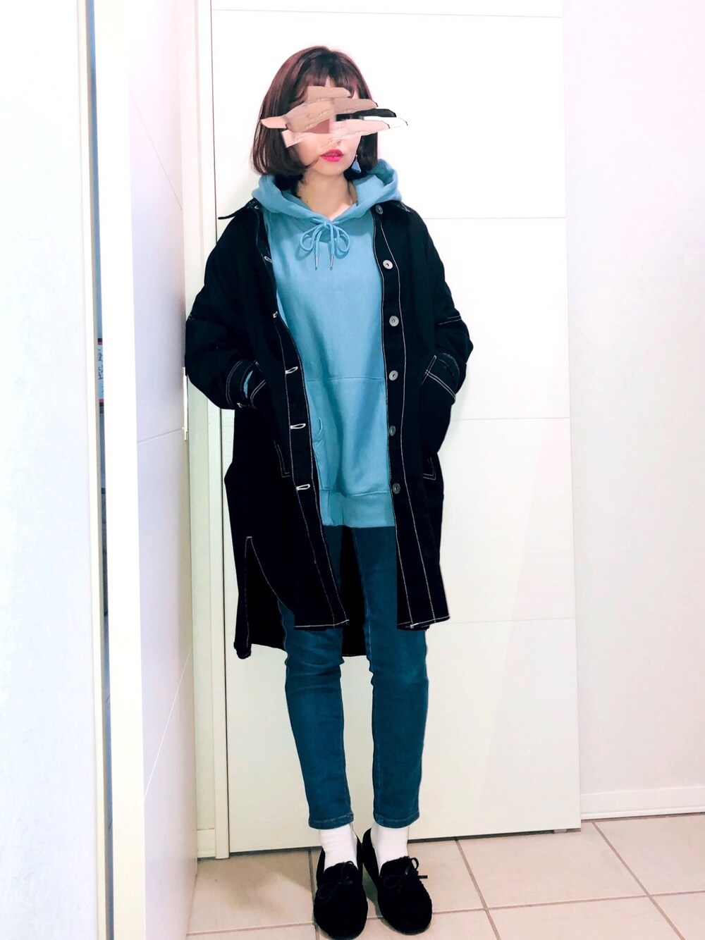 ブラック系のミリタリージャケット、ブルー系のパーカー、ブルー系のデニムパンツを着用したレディースの冬コーディネートの1枚目の写真