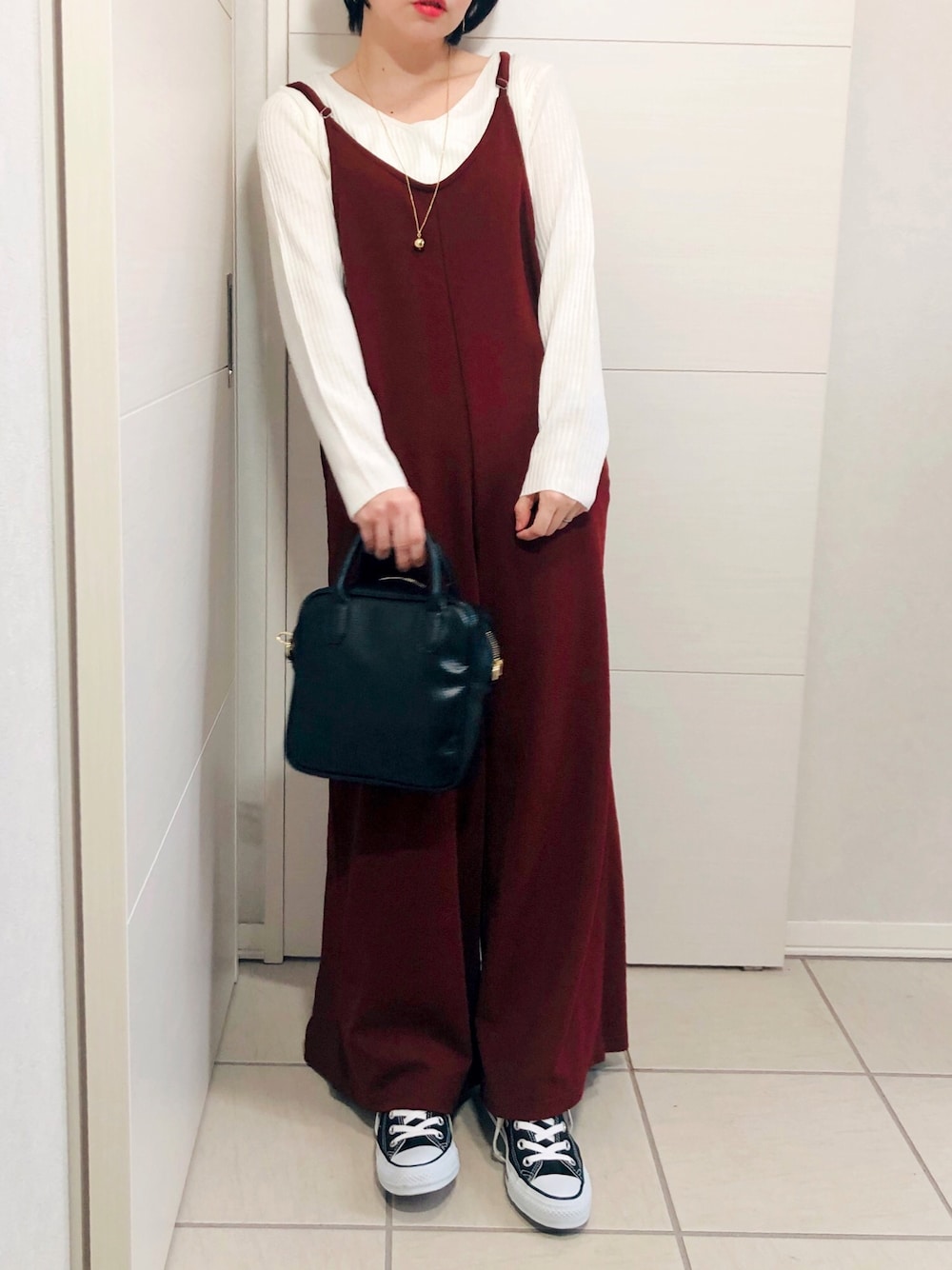 レッド系のサロペット/オーバーオール、ホワイト系のニット/セーター、ブラック系のスニーカーを着用したレディースの秋コーディネートの1枚目の写真