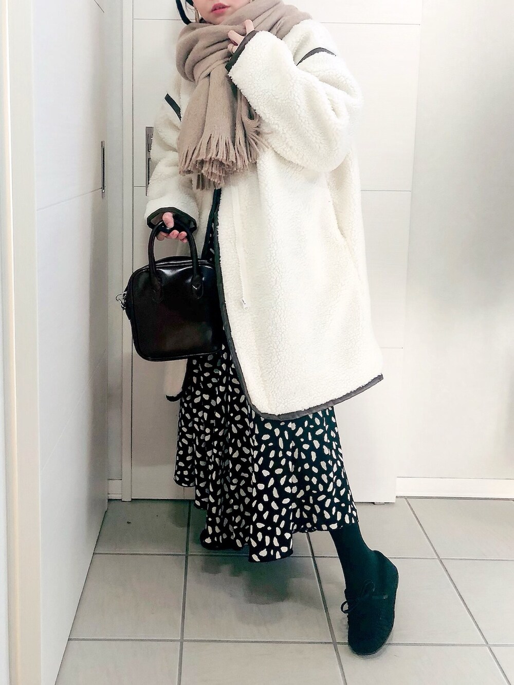 ホワイト系のノーカラージャケット、ブラック系のスカート、ブラック系のモカシン/デッキシューズを着用したレディースの冬コーディネートの1枚目の写真