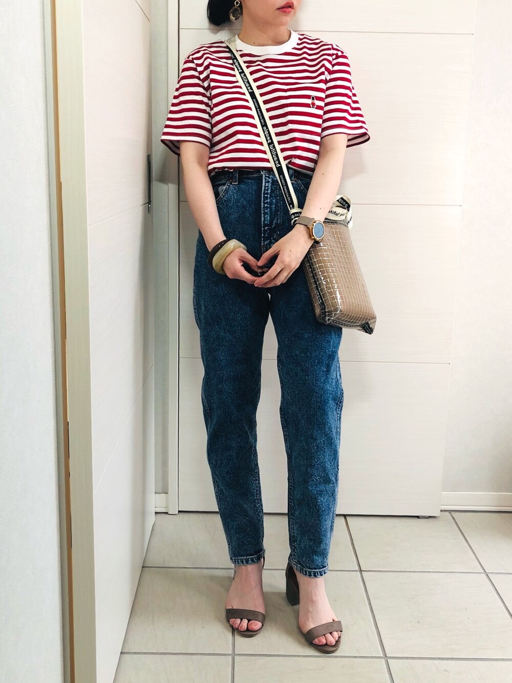 レッド系のTシャツ/カットソー、ブルー系のデニムパンツ、ベージュ系のサンダルを着用したレディースの春コーディネートの1枚目の写真