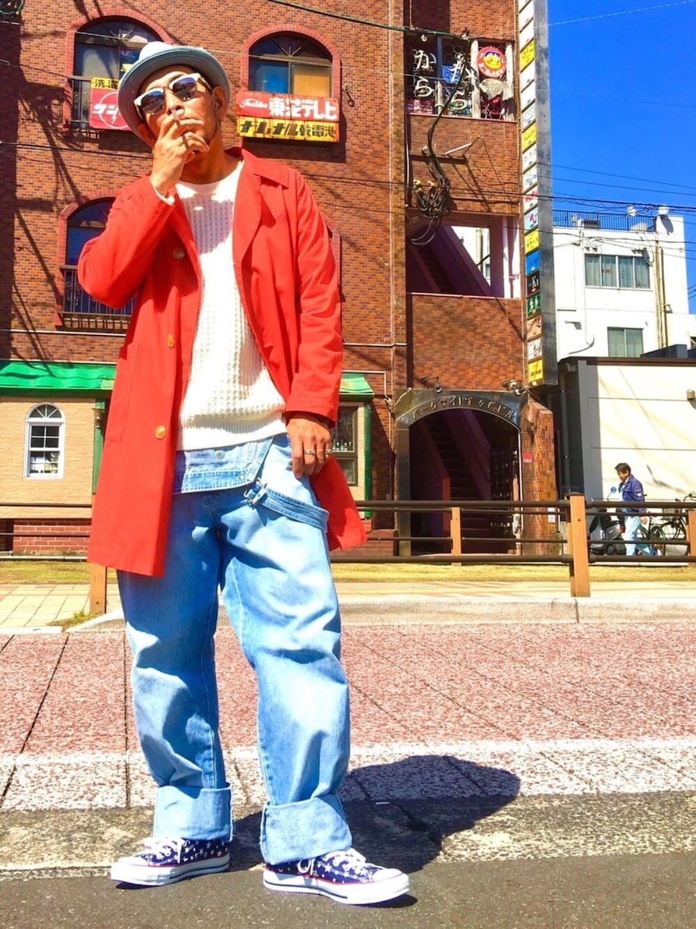 ブルー系のサロペット/オーバーオール、レッド系のステンカラーコート、ホワイト系のニット/セーターを着用したメンズの春コーディネートの1枚目の写真