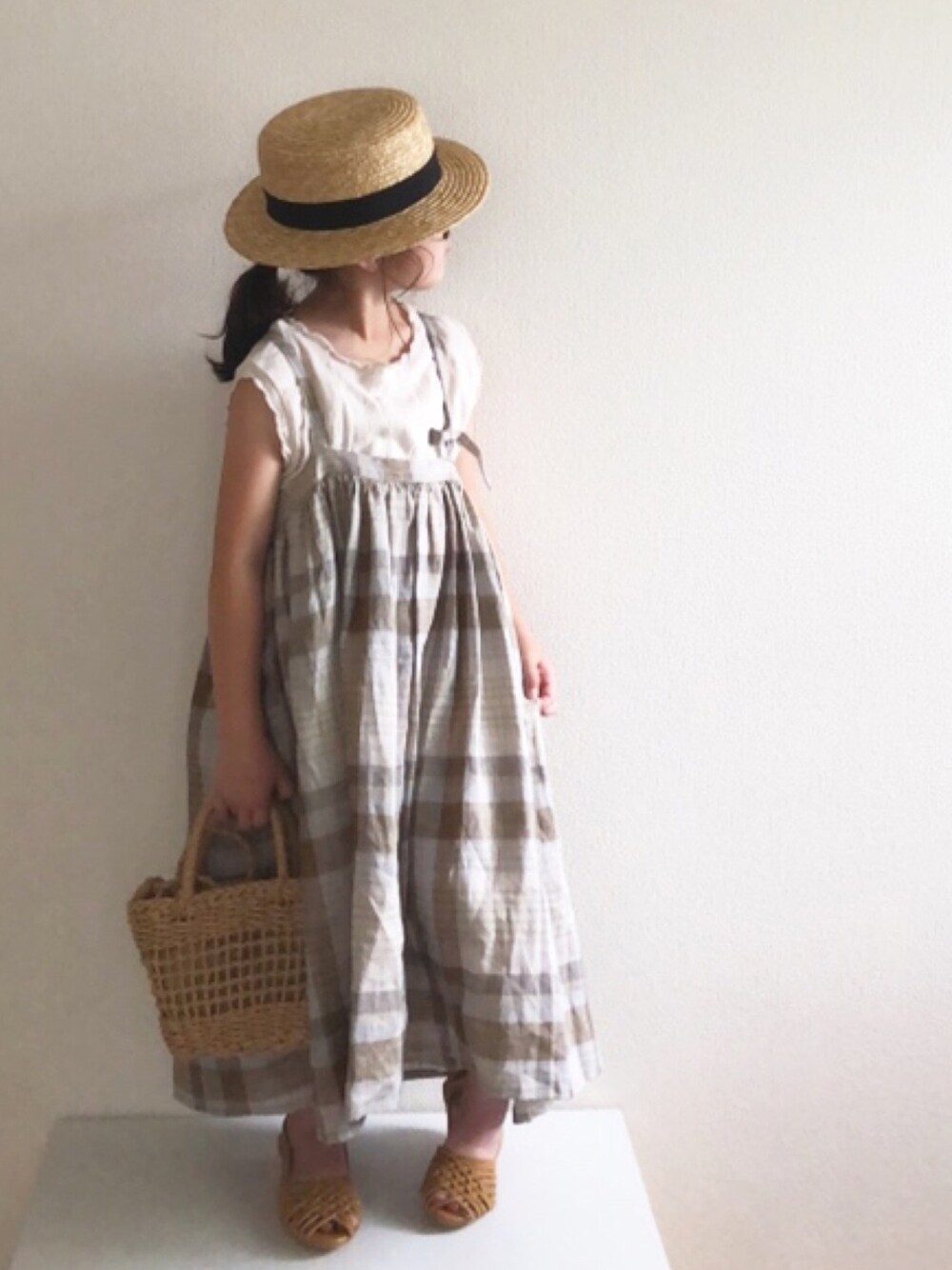 イエロー系のサンダル、ホワイト系のトップス、ブラウン系のワンピース/ドレスを着用したキッズの夏コーディネートの1枚目の写真