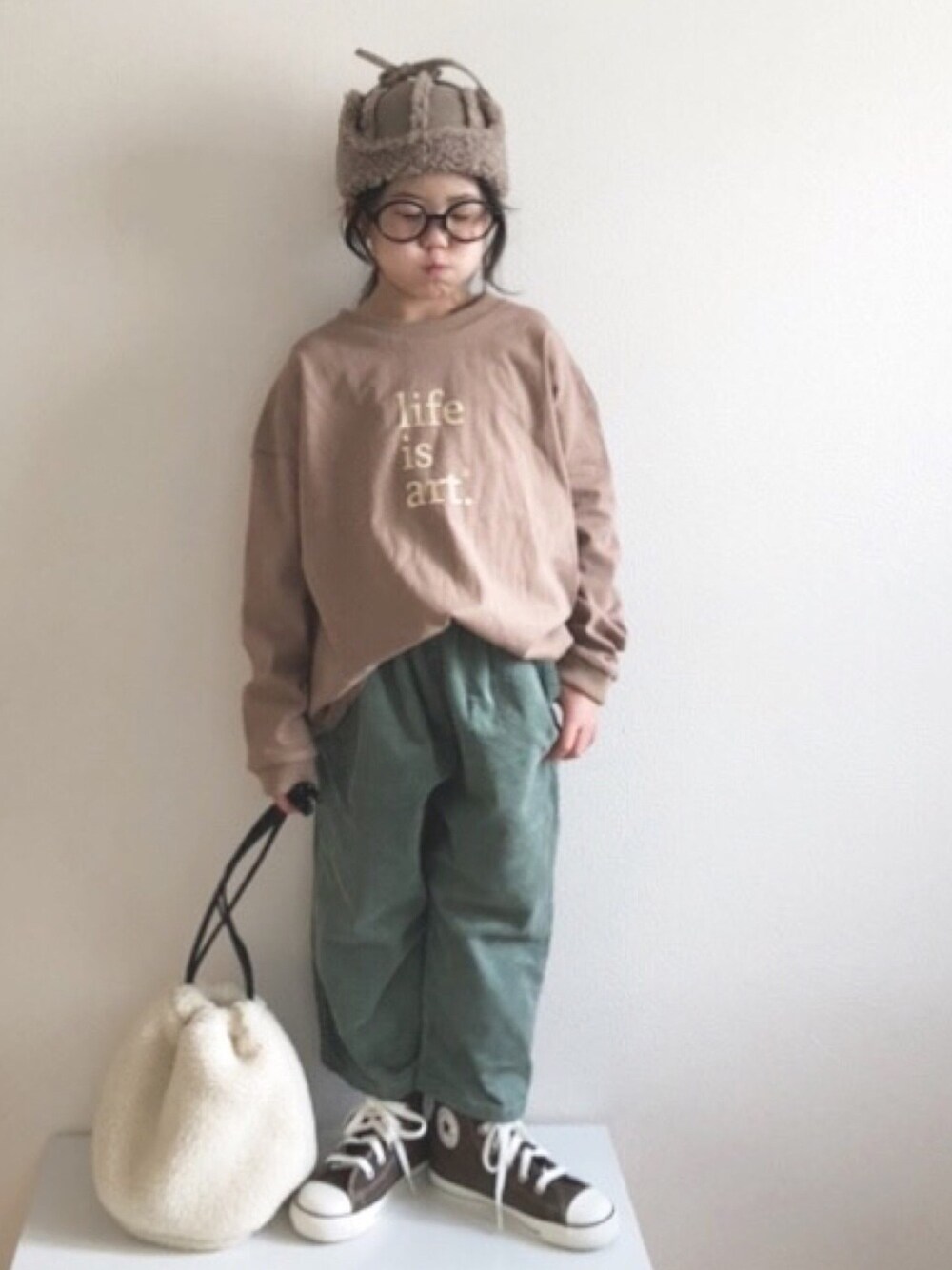 「グリーンフェス❶❶、フライトキャップ、めがね、くすみカラー、コンバース、ハイカットスニーカー、ゆるコーデ、巾着バッグ、ボア、ロンT」｜「antiquaのプリントT　完全オリジナルのロゴデザイン。ゆるっとオーバーサイズでこなれ感をプラスして。（Tシャツ/カットソー、ブラウン系）」を使った、nami *さん（キッズ・110cm）の冬コーディネートの1枚目の写真