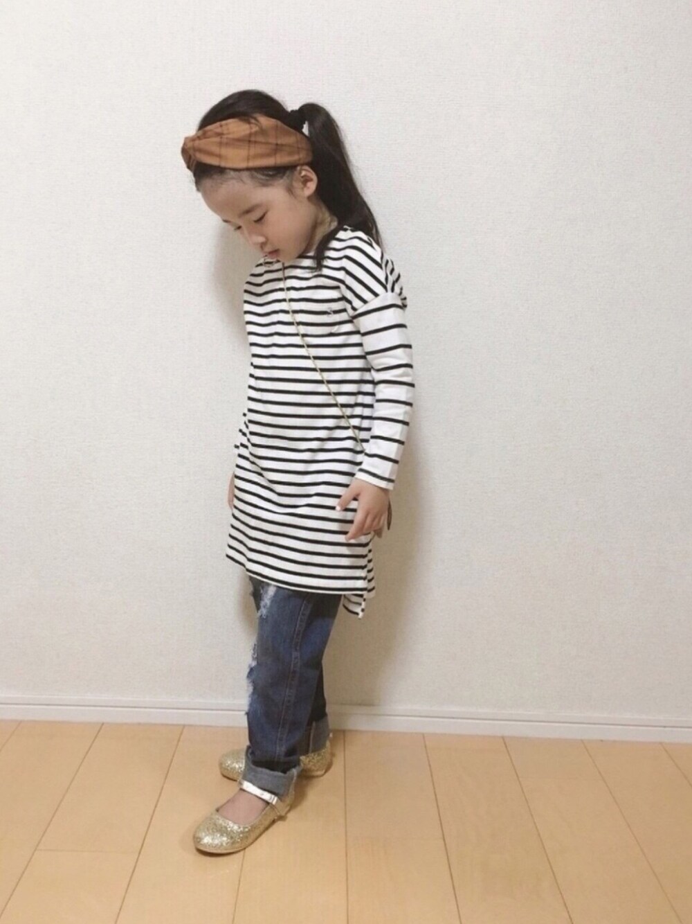 ホワイト系のワンピース、ブルー系のデニムパンツ、ゴールド系のバレエシューズを着用したキッズの秋コーディネートの1枚目の写真