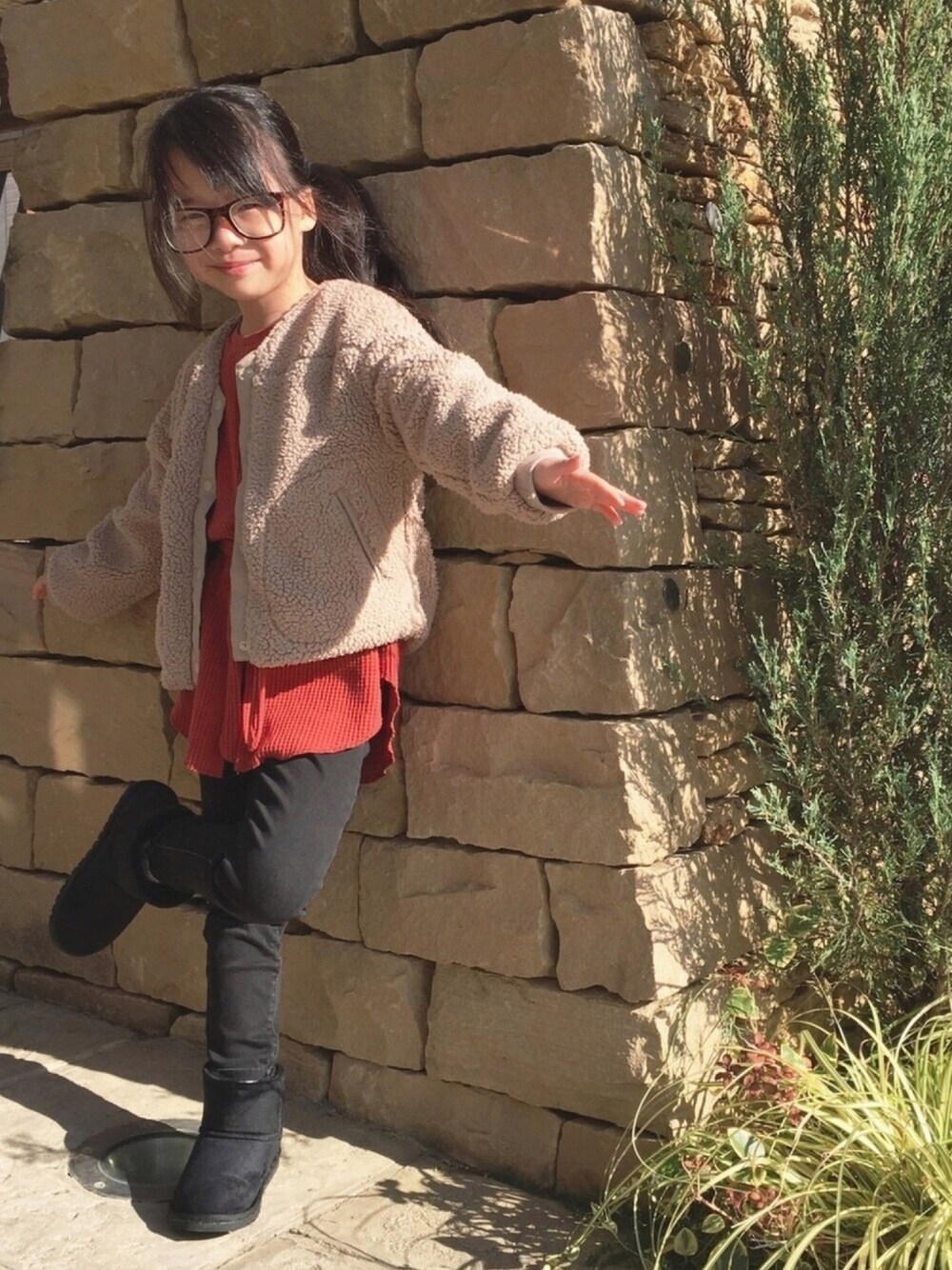 オレンジ系のチュニック、ブラック系のパンツ、ブラック系のブーツを着用したキッズの秋コーディネートの1枚目の写真