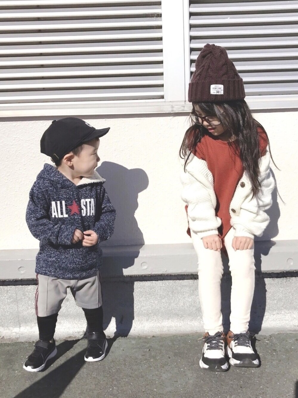 ホワイト系のカーディガン/ボレロ、オレンジ系のチュニック、ホワイト系のスニーカーを着用したキッズの冬コーディネートの1枚目の写真