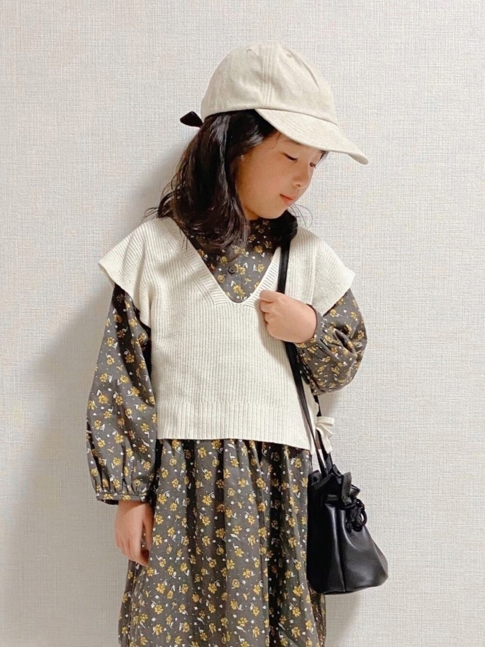 「キッズコーデ、おんなのこ、花柄、シャツワンピ、ワンピース、ベスト、キャップ、巾着バッグ、ガーリー、チェッカーずまつり2020秋　告知」｜「petit mainのケーブルニットベスト×花柄ワンピースセット（ワンピース、ブラック系）」を使った、naaaさん（キッズ・124cm）の秋コーディネートの1枚目の写真