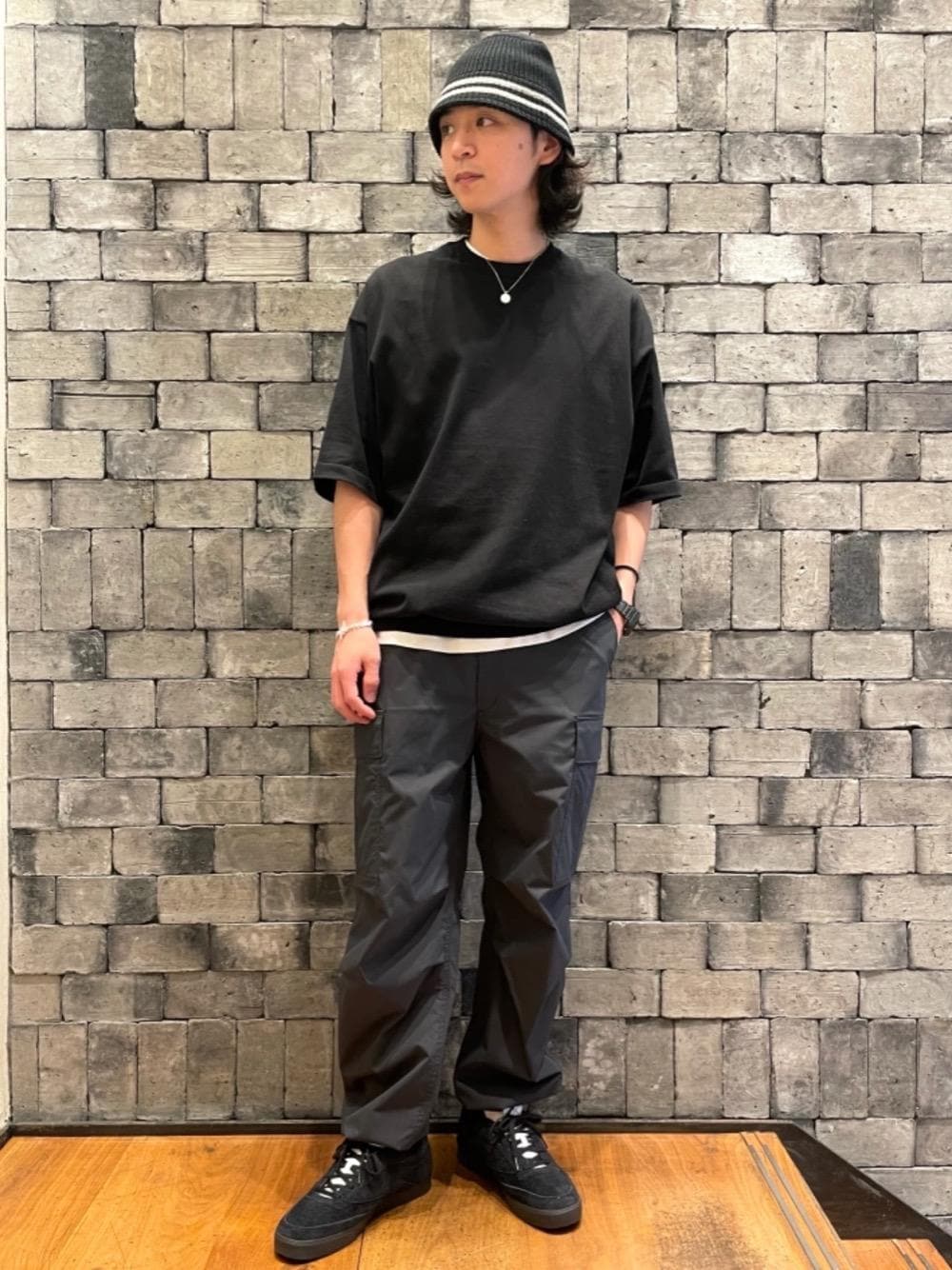 ブラック系のカーゴパンツ、ブラック系のスニーカー、ブラック系のデジタル腕時計を着用したメンズの春コーディネートの1枚目の写真