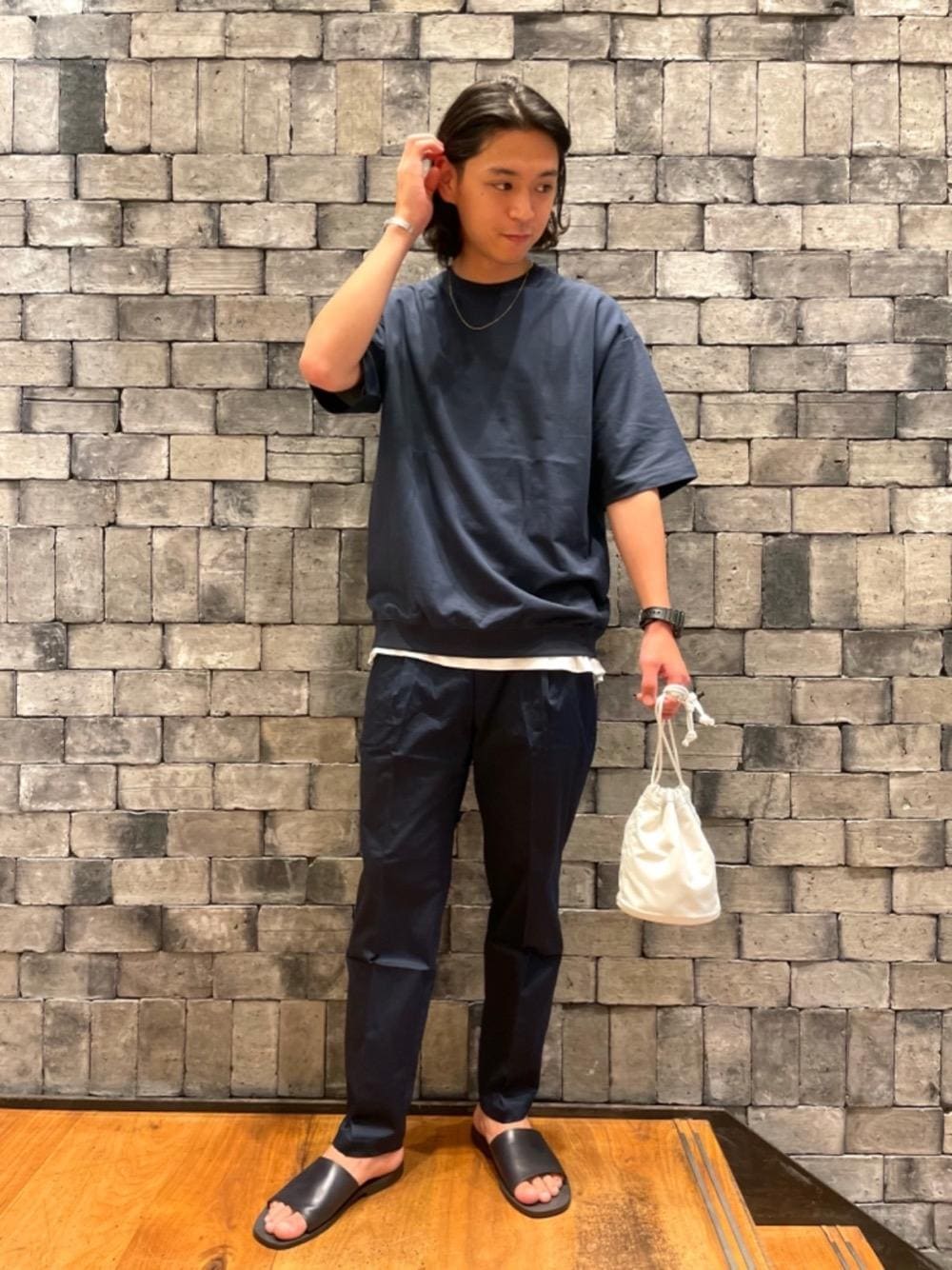 ホワイト系のハンドバッグ、ブラック系のサンダル、ブルー系のTシャツ/カットソーを着用したメンズの夏コーディネートの1枚目の写真