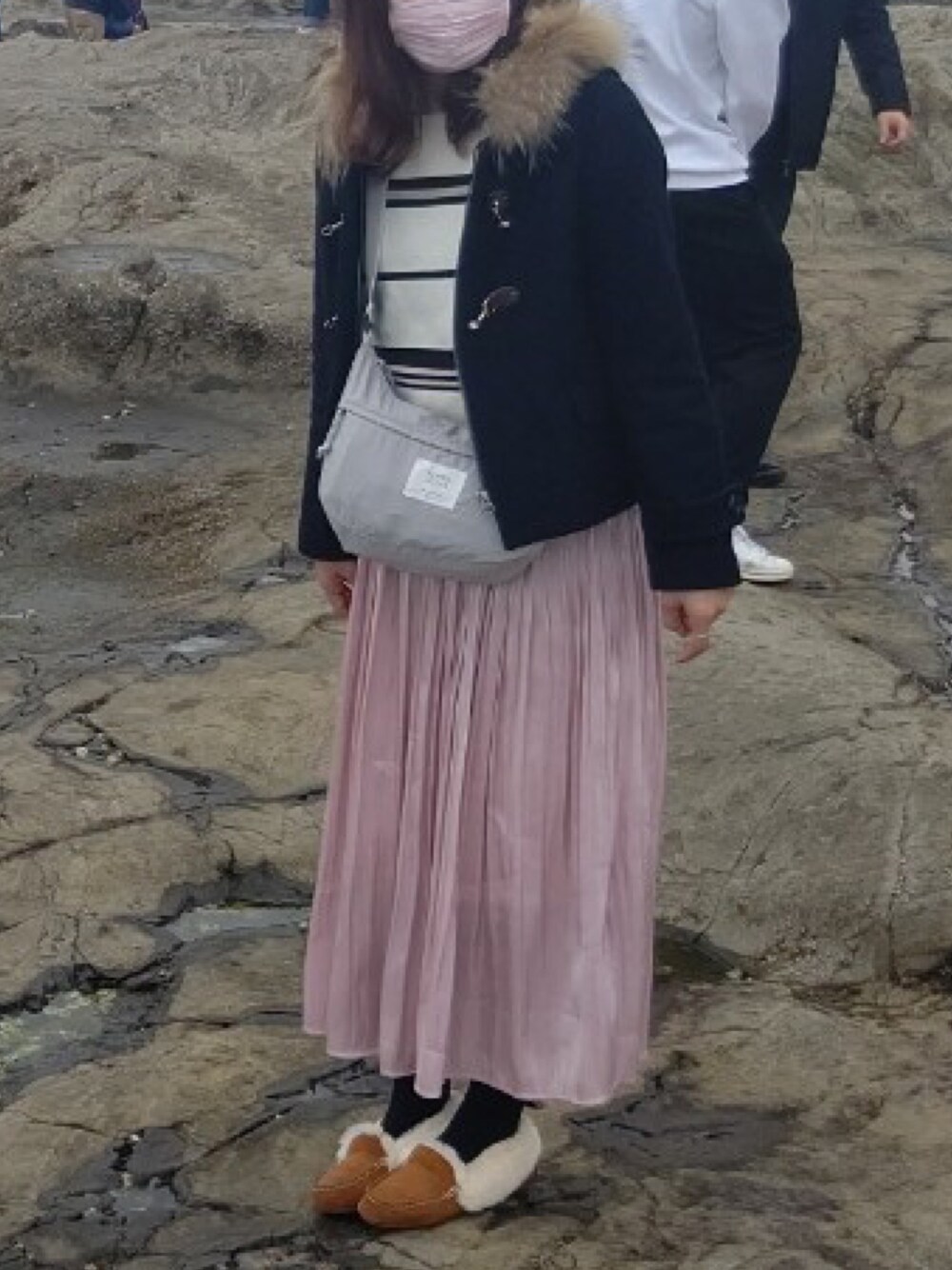 ピンク系のスカート、ブラウン系のモカシン/デッキシューズ、グレー系のショルダーバッグを着用したレディースの冬コーディネートの1枚目の写真