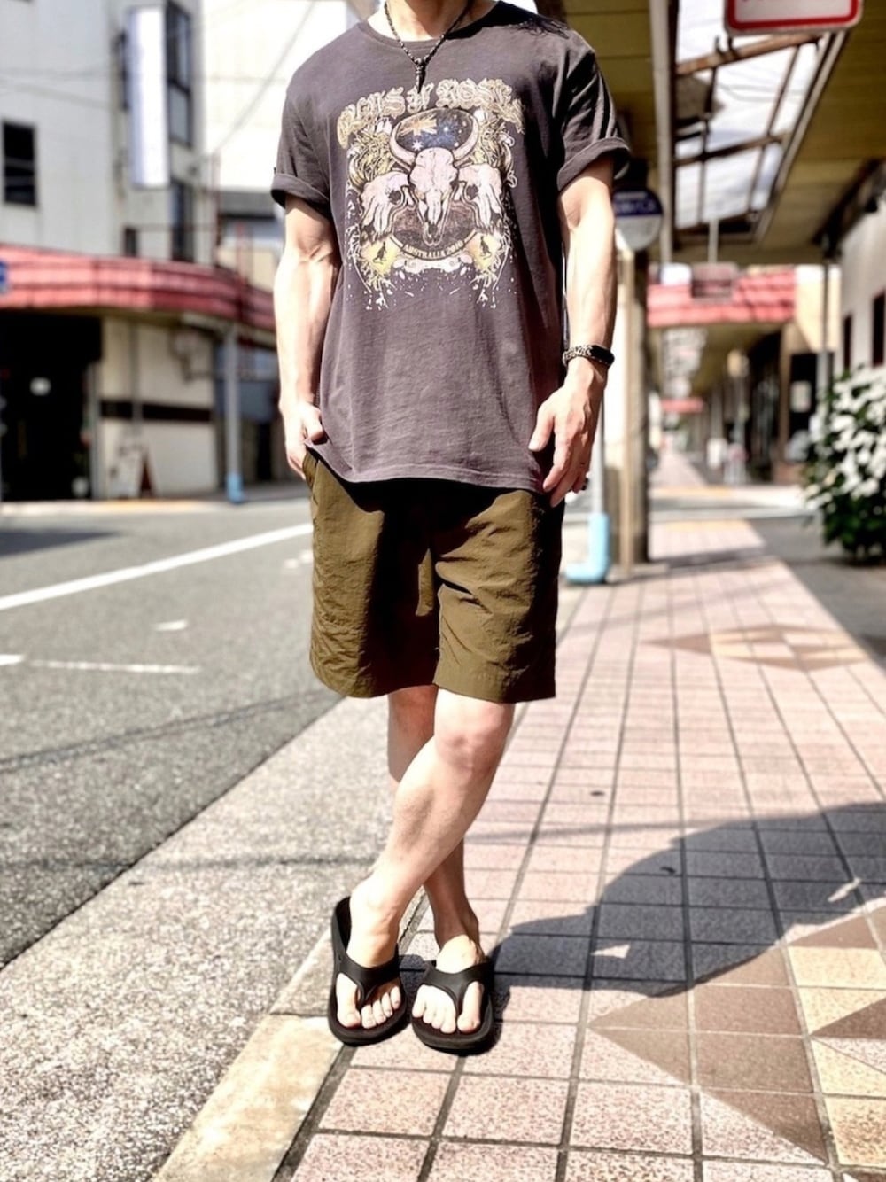 ブラック系のTシャツ/カットソー、グリーン系のその他パンツ、ブラック系のサンダルを着用したメンズの秋コーディネートの1枚目の写真