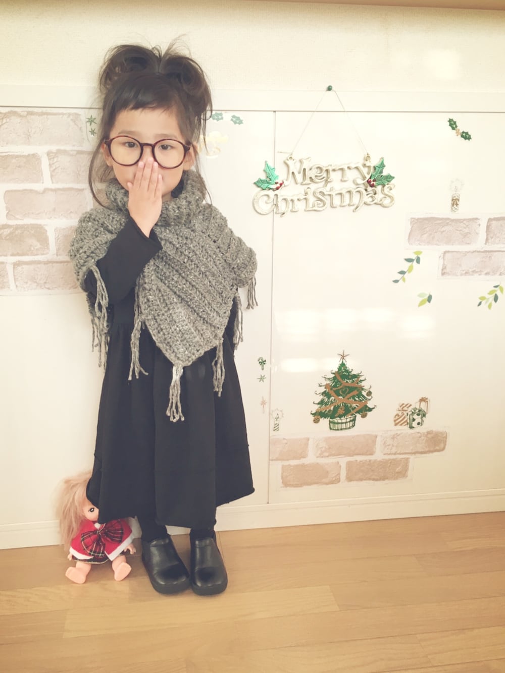 ブラック系のワンピース、ブラック系のブーティ、グレー系のレインコート/ポンチョを着用したキッズの冬コーディネートの1枚目の写真