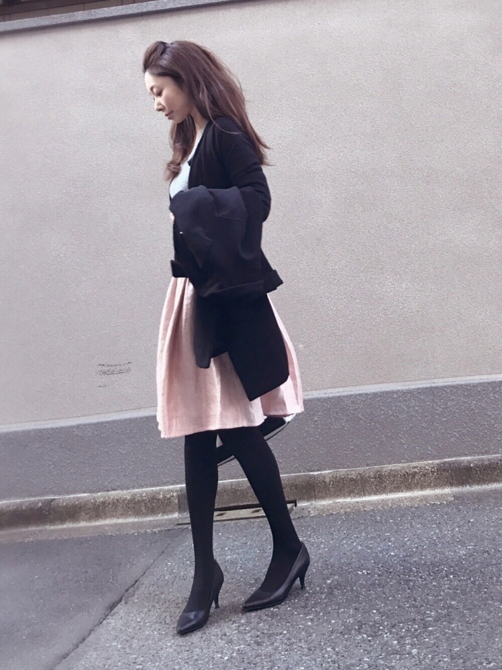 グレー系のニット/セーター、ピンク系のスカート、ブラック系のパンプスを着用したレディースの冬コーディネートの1枚目の写真