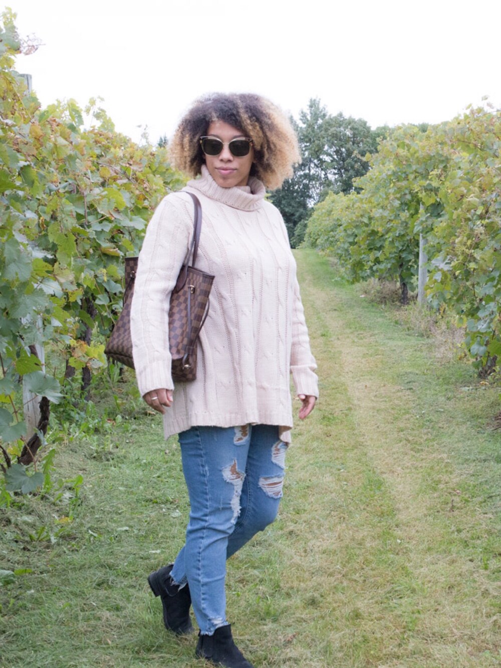 ブラック系のブーツ、ブラウン系のトートバッグ、ベージュ系のニット/セーターを着用したレディースの秋コーディネートの1枚目の写真