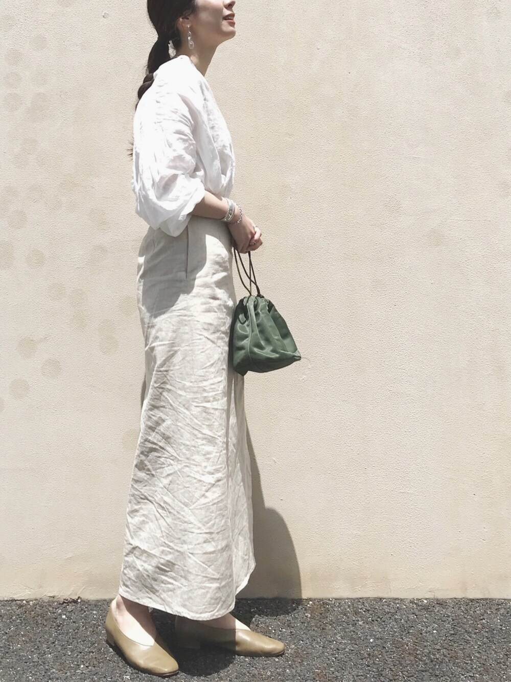 グリーン系のショルダーバッグ、ベージュ系のスカート、ホワイト系のシャツ/ブラウスを着用したレディースの春コーディネートの1枚目の写真