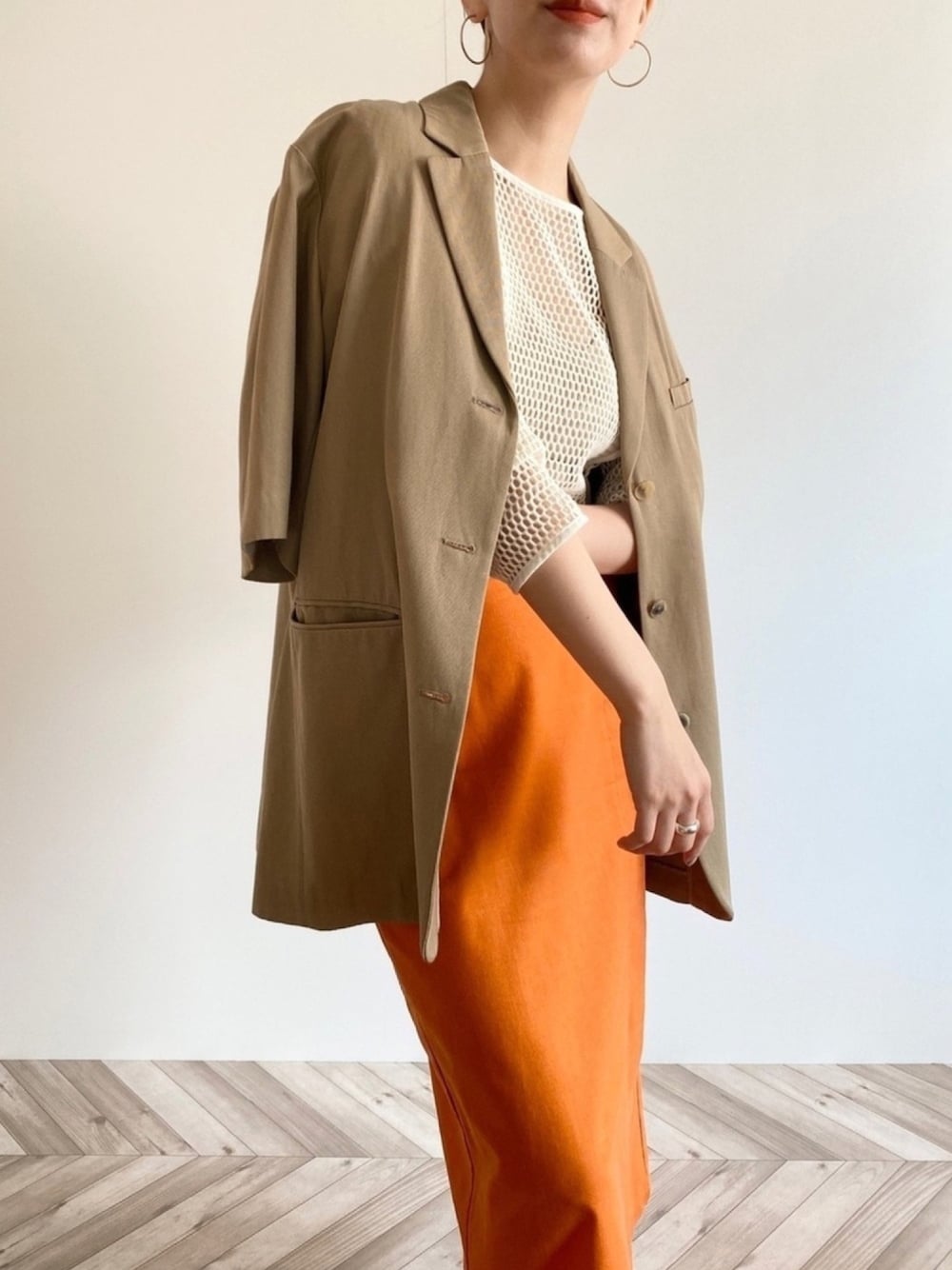 ホワイト系のTシャツ/カットソー、オレンジ系のスカート、シルバー系のリングを着用したレディースの春コーディネートの1枚目の写真