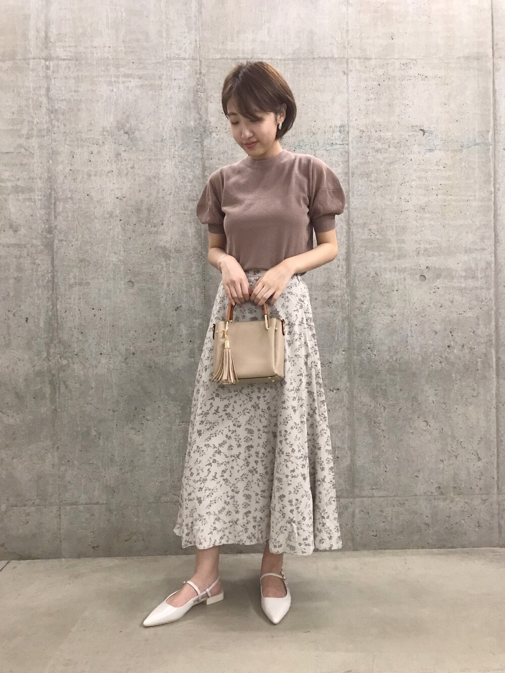 ブラウン系のトートバッグ、ピンク系のTシャツ/カットソー、ベージュ系のスカートを着用したレディースの夏コーディネートの1枚目の写真