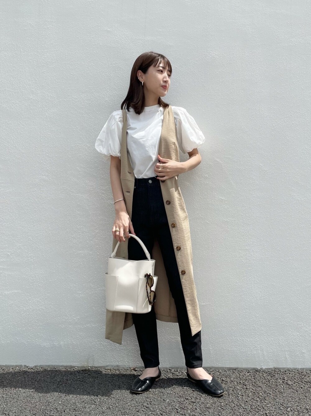 ベージュ系のジャンパースカート、ホワイト系のTシャツ/カットソー、ブラック系のショルダーバッグを着用したレディースの春コーディネートの1枚目の写真