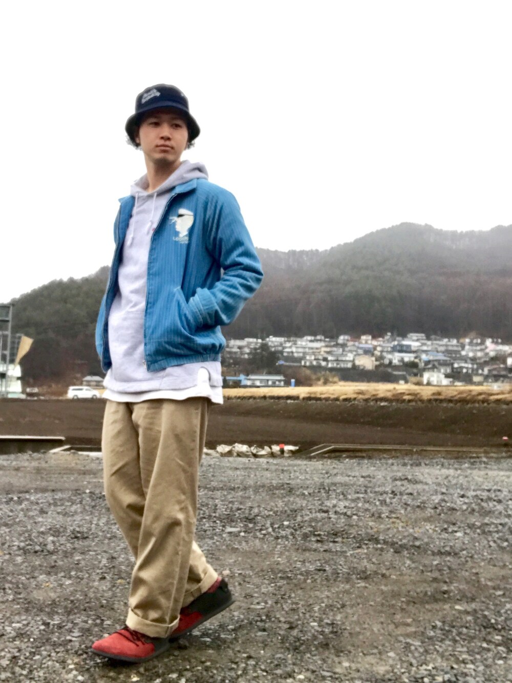 グレー系のパーカー、ブルー系のその他アウター、ベージュ系のその他パンツを着用したメンズの春コーディネートの1枚目の写真