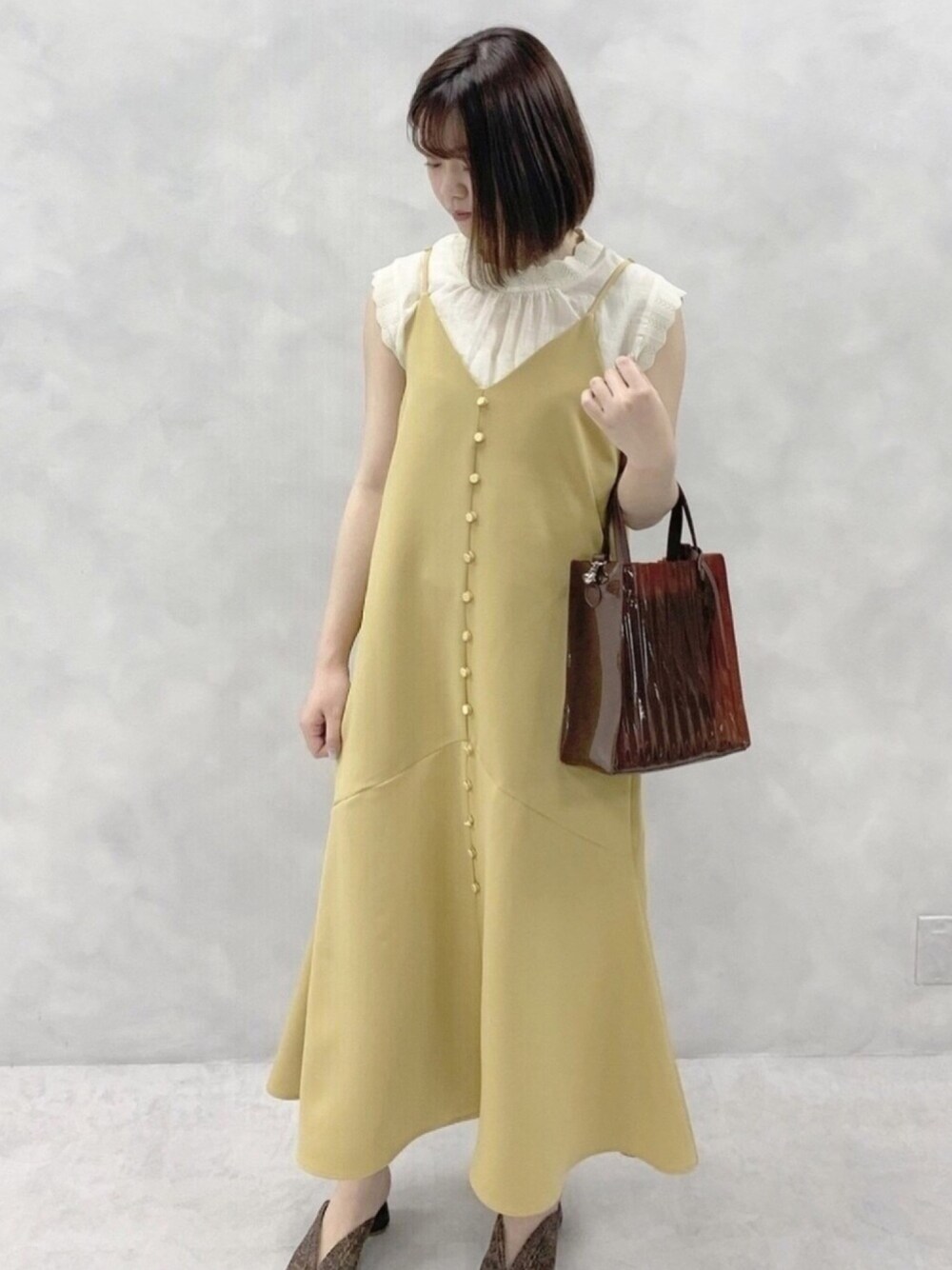 イエロー系のワンピース、ホワイト系のシャツ/ブラウス、ブラウン系のその他シューズを着用したレディースの春コーディネートの1枚目の写真