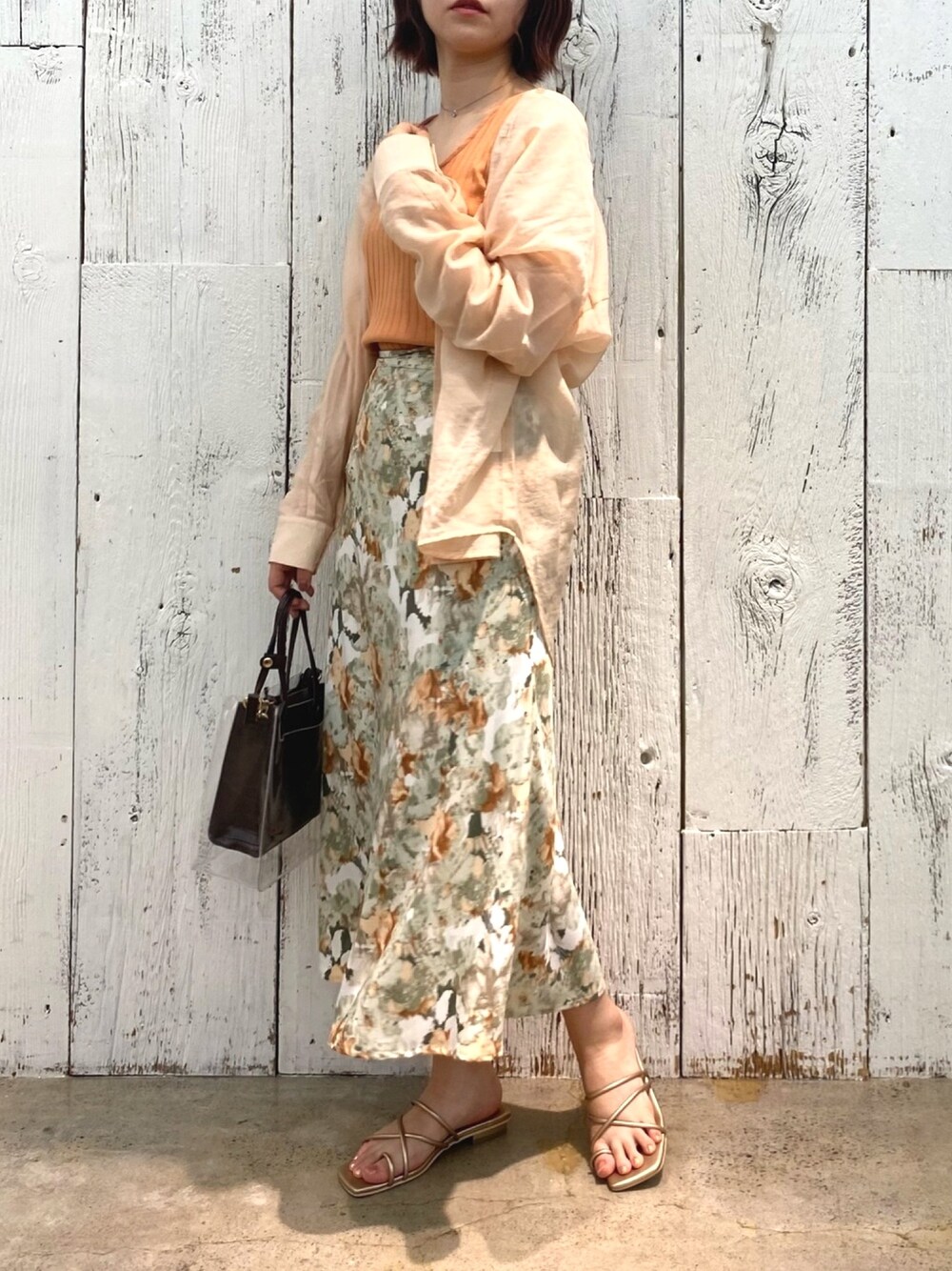 オレンジ系のシャツ/ブラウス、ブラウン系のトートバッグ、ゴールド系のサンダルを着用したレディースの春コーディネートの1枚目の写真