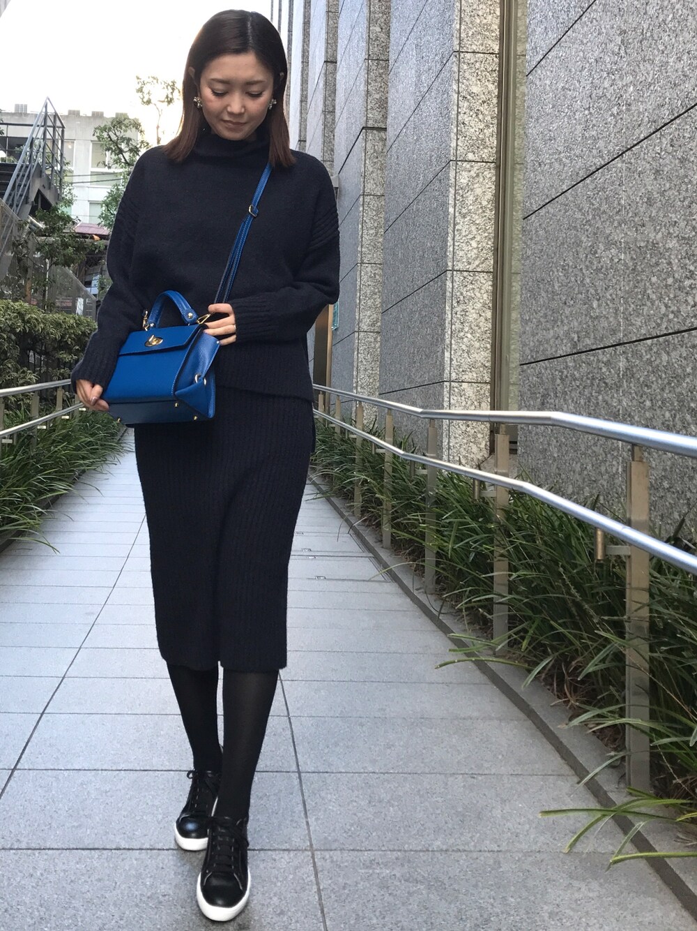 ブルー系のニット/セーター、ブルー系のスカート、ブラック系のスニーカーを着用したレディースの冬コーディネートの1枚目の写真