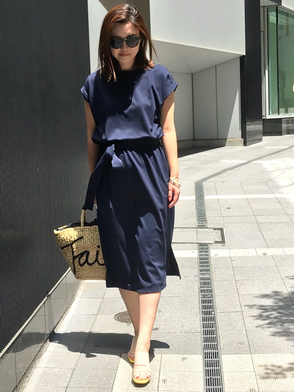ブルー系のワンピース、ベージュ系のかごバッグ、イエロー系のサンダルを着用したレディースの夏コーディネートの1枚目の写真