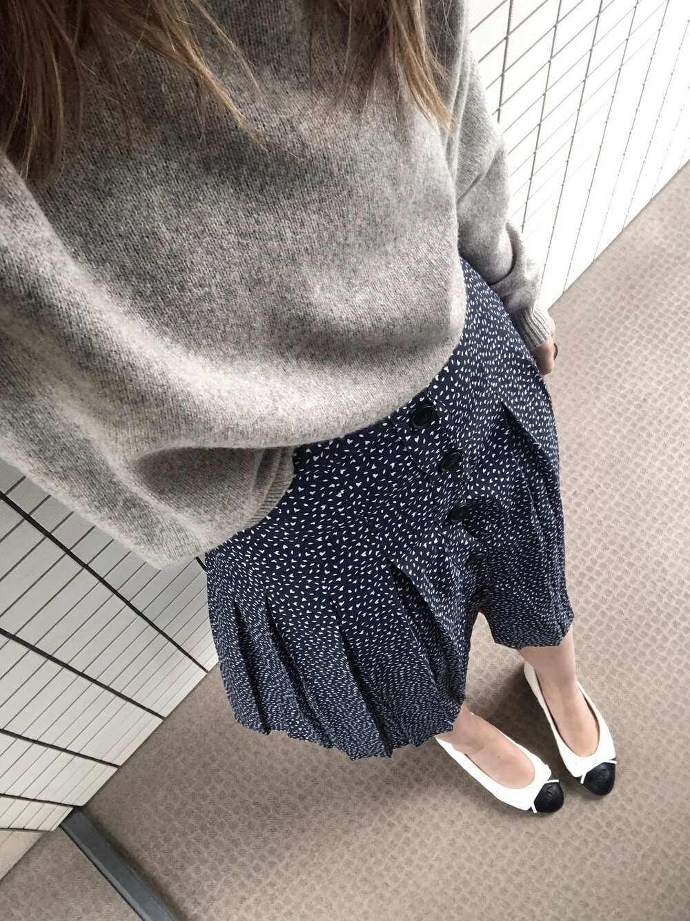 グレー系のニット/セーター、ブルー系のスカートを着用したレディースの秋コーディネートの1枚目の写真