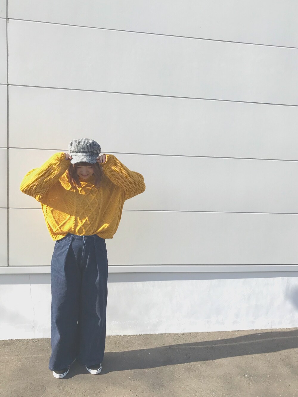 イエロー系のニット/セーター、ブルー系のデニムパンツ、ブラック系のキャスケットを着用したレディースの冬コーディネートの1枚目の写真