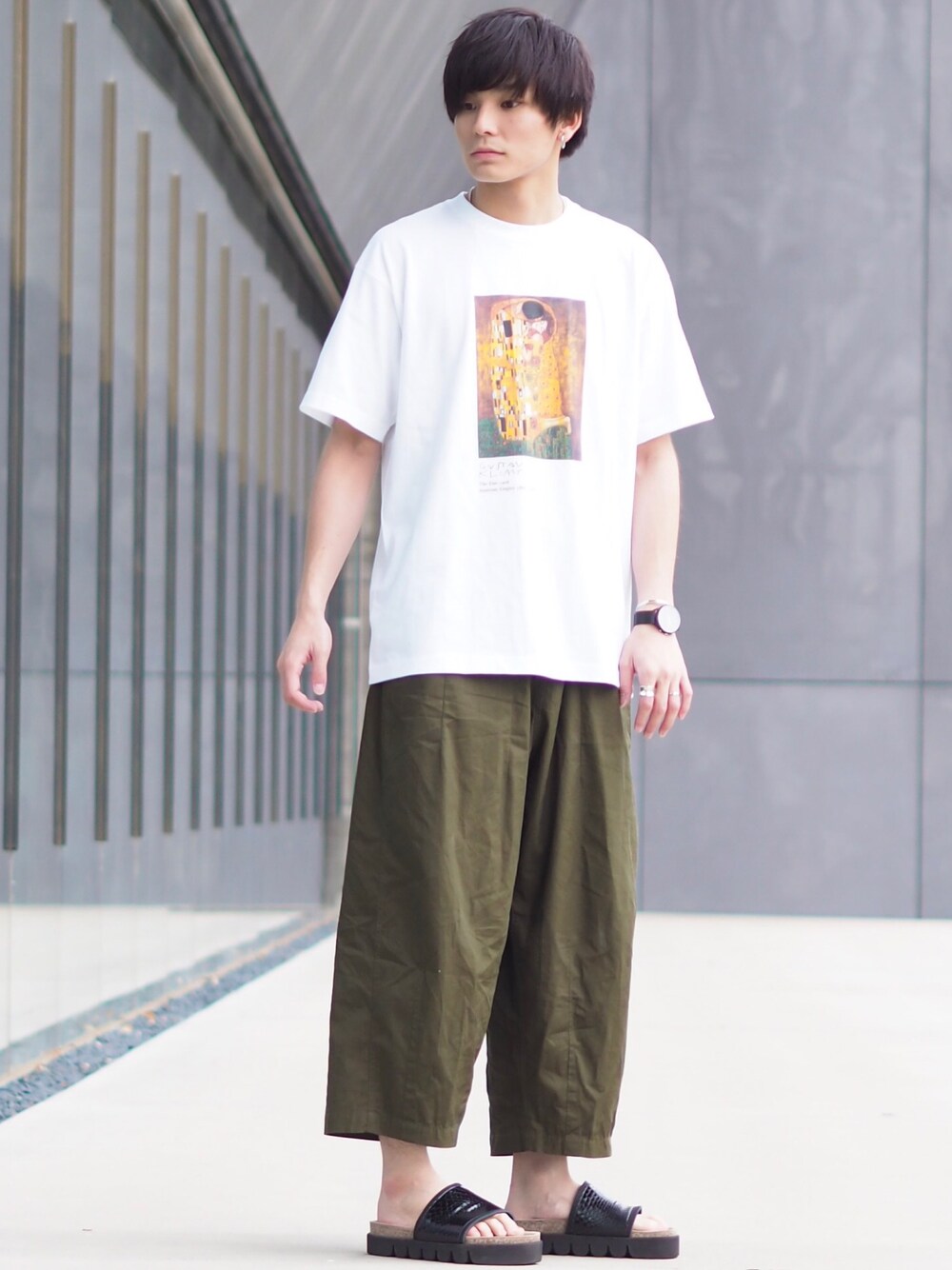 ホワイト系のTシャツ/カットソー、グリーン系のチノパンツ、ブラック系のサンダルを着用したメンズの夏コーディネートの1枚目の写真