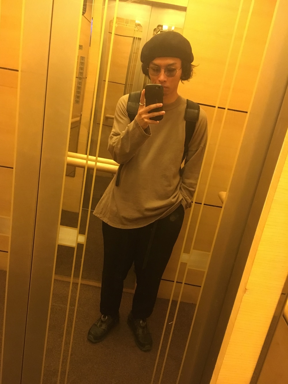 ベージュ系のTシャツ/カットソー、ブラック系のスラックス、ブラック系のスニーカーを着用したメンズの春コーディネートの1枚目の写真