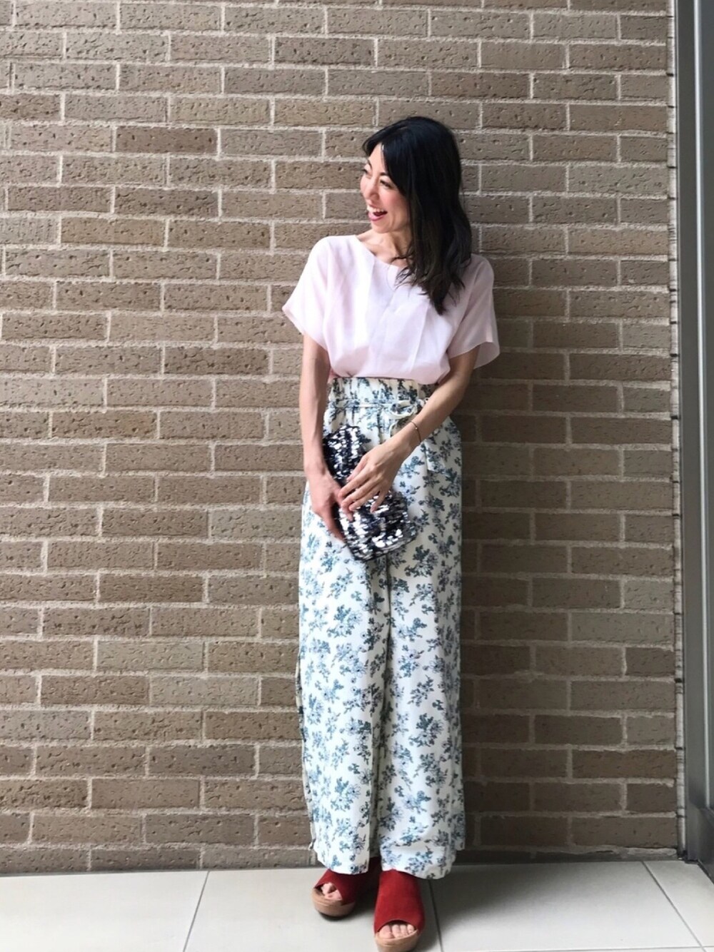 ホワイト系のその他パンツ、ブラウン系のサンダル、ブラック系のクラッチバッグを着用したレディースの春コーディネートの1枚目の写真