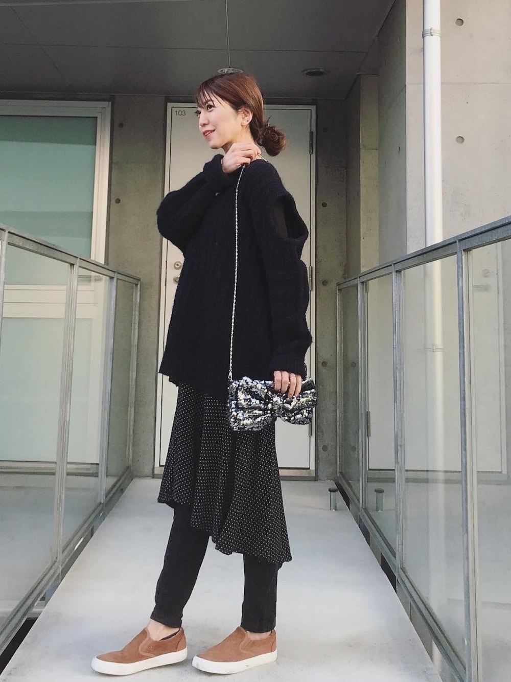 ブラウン系のシューズ、ブラック系のワンピース、ブラック系のクラッチバッグを着用したレディースの冬コーディネートの1枚目の写真